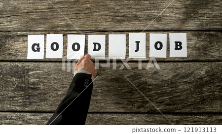 Business leader assembling phrase GOOD JOB with white cards with letters on them on rustic wooden background 121913113