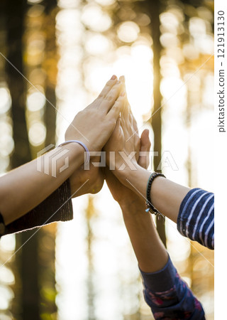 Closeup of four female hands joined together high up in the air 121913130