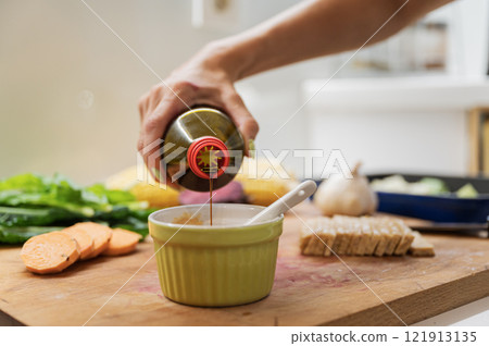 Closeup view of a woman pouring soya sauce into a cup 121913135