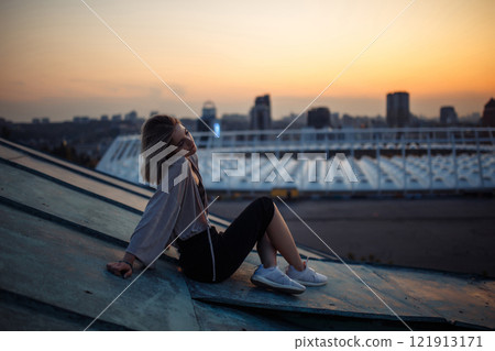 Young woman in roof enjoying sunset, freedom city atmosphere. People, lifestyle, relaxation concept. 121913171