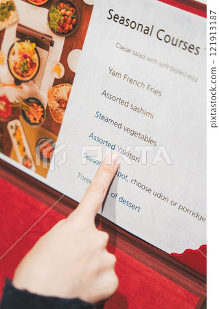 A female customer looks at the menu and makes a selection [Photo courtesy of Seafood Izakaya Gyoruko] 121913187