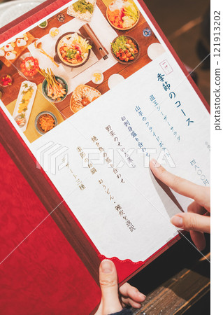 A female customer looks at the menu and makes a selection [Photo courtesy of Seafood Izakaya Gyoruko] 121913202
