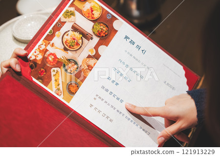 A female customer looks at the menu and makes a selection [Photo courtesy of Seafood Izakaya Gyoruko] 121913229
