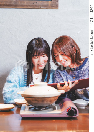 Two young women thinking about their next order in front of a crab hotpot [Photo courtesy of Seafood Izakaya Gyoruko] 121913244