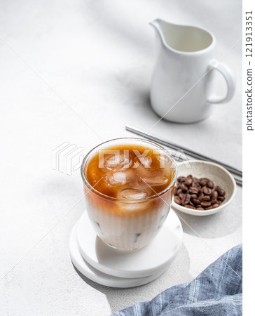 Iced coffee latte in a glass with milk on a light background with coffee beans Iced coffee latte in a glass with milk on a light background with coffee beans 121913351