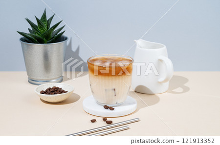 Cold latte coffee in a glass with milk on a yellow and blue background with coffee beans 121913352