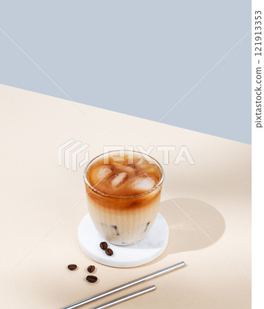 Iced coffee latte in a glass with milk on a yellow and blue background with coffee beans 121913353