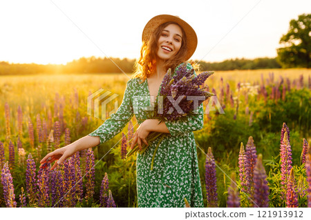 A beautiful woman with a bouquet of lupins, collects flowers, inhales fresh floral air. A beautiful woman with a bouquet of lupins, collects flowers, inhales fresh floral air. 121913912