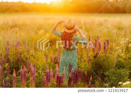 A beautiful woman with a bouquet of lupins, collects flowers, inhales fresh floral air. 121913917