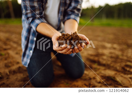 Soil is in the strong hands of a farmer on a black field. Agriculture or gardening concept. 121914062