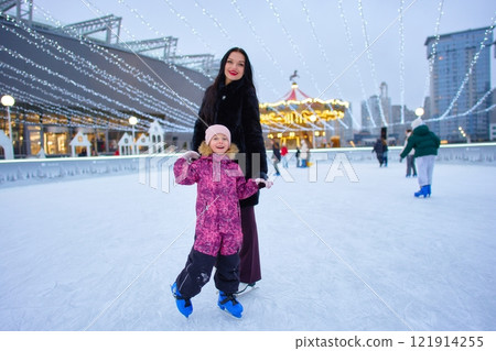 Joyful ice skating adventure in a festive rink during winter evening 121914255