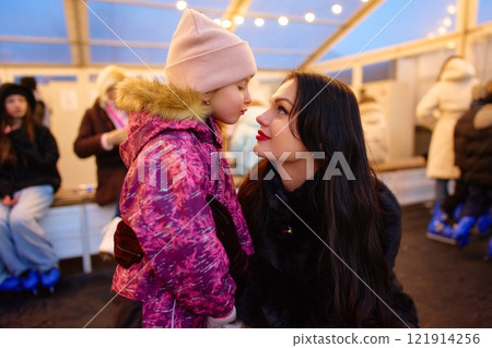 Mother and daughter share a joyful moment at a winter skating rink Mother and daughter share a joyful moment at a winter skating rink 121914256