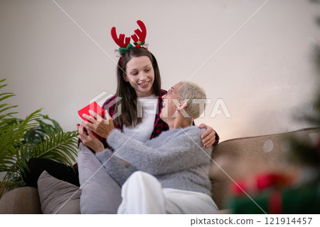Intergenerational Holiday Bonding Daughter and Grandmother Exchanging Gifts 121914457