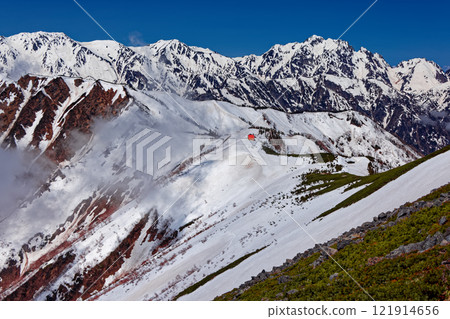 Snow-covered Mt. Tateyama, Mt. Tsurugi and Taneike Sanso mountain lodge seen from the southern ridge of Mt. Jigatake in the Northern Alps 121914656