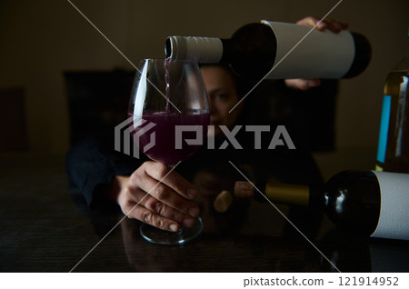 Wine being poured into a glass with a person in the background 121914952