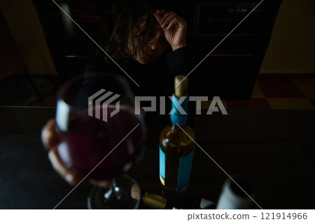 Woman Reflecting Over a Glass of Wine in Dim Lighting Woman Reflecting Over a Glass of Wine in Dim Lighting 121914966