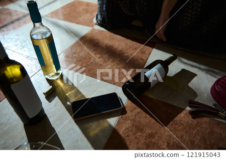 Scattered Wine Bottles and Phone on a Tiled Floor Scattered Wine Bottles and Phone on a Tiled Floor 121915043