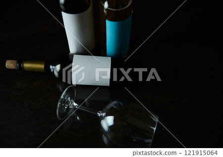 Dark composition of wine bottles with a glass on a reflective surface Dark composition of wine bottles with a glass on a reflective surface 121915064