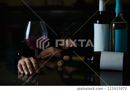 A person experiencing the effects of alcohol consumption in a somber setting 121915072