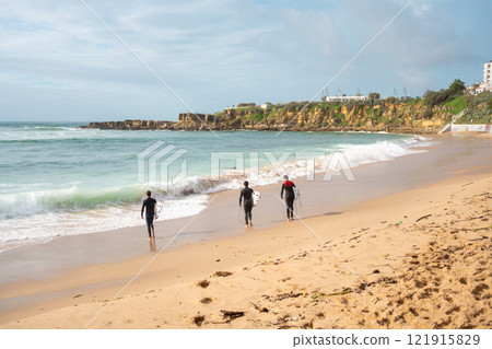 Anonymous surfers walking on sandy seashore at Anonymous surfers walking on sandy seashore at 121915829