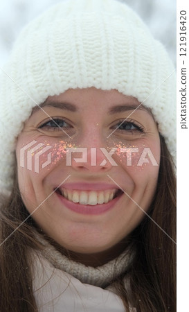 Portrait of woman in warm white knitted hat outdoors in winter. Young woman smiling and enjoying beautiful weather and first snow, laughing and looking at camera. Active winter recreation. Wide Portrait of woman in warm white knitted hat outdoors in winter. Young woman smiling and enjoying beautiful weather and first snow, laughing and looking at camera. Active winter recreation. Wide 121916420