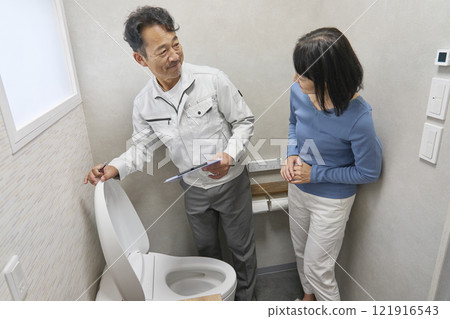 A woman asking a repairman to fix a broken toilet A woman asking a repairman to fix a broken toilet 121916543
