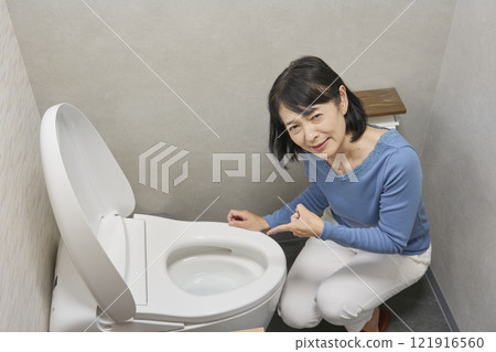 Woman troubled by toilet malfunction, looking at camera Woman troubled by toilet malfunction, looking at camera 121916560