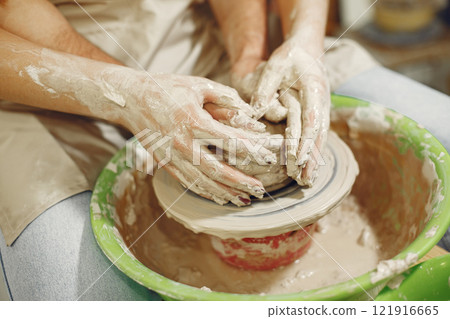 Mutual creative work. Hands creating a bowl on a pottery wheel in a clay studio. Mutual creative work. Hands creating a bowl on a pottery wheel in a clay studio. 121916665