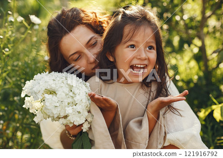 Family in a summer garden. Sensual photo. Cute little girl. Woman with bouquet. 121916792