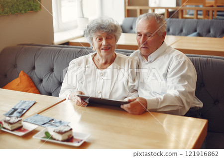 Grandparents in a cafe. Old people use the laptop. Senior in a white shirt. 121916862