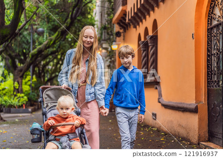 Mother with her two sons exploring lush streets of Condesa, Mexico City. Family adventure in a vibrant urban oasis. Travel, family bonding, and urban greenery concept in Latin America Mother with her two sons exploring lush streets of Condesa, Mexico City. Family adventure in a vibrant urban oasis. Travel, family bonding, and urban greenery concept in Latin America 121916937