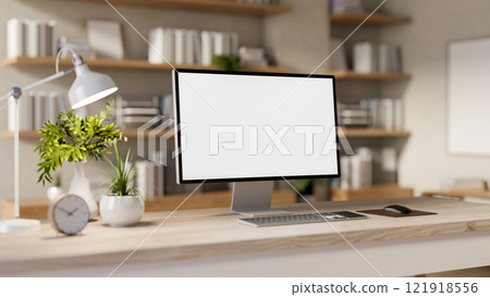 A computer with a white screen mockup and decor placed on a wooden desk in a room. 121918556
