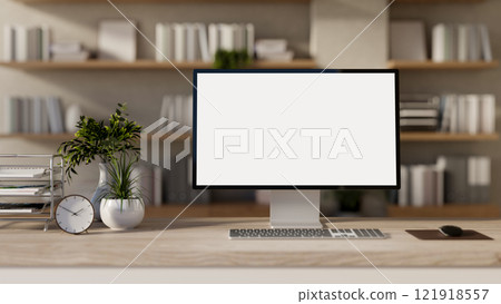 A computer with a white screen mockup and decor placed on a wooden desk in a room. 121918557