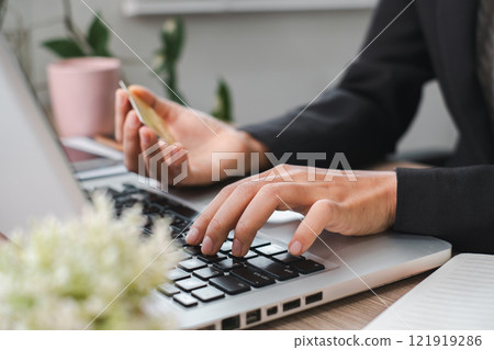 Business Professional Using Laptop and Credit Card for Online Shopping in Modern Office Environment with Green Plants 121919286