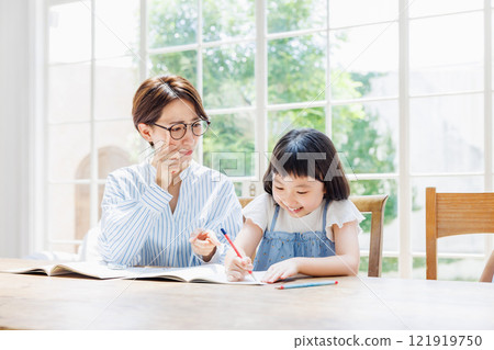 A mother who gives a strict look to an elementary school girl studying A mother who gives a strict look to an elementary school girl studying 121919750