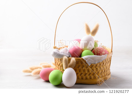 Easter eggs with bunny rabbit ears in basket on white background Easter eggs with bunny rabbit ears in basket on white background 121920277