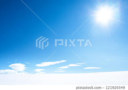 A simple landscape of snowy fields, blue skies and the sun, typical of Hokkaido in winter. 121920349