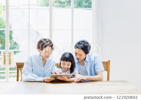 Daughter and parents studying using a tablet 121920602