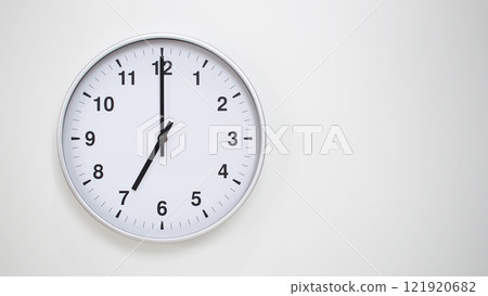 Minimalist White Clock with Silver Frame Striking 19.00/07.00 on White Background. Perfect for Time Management and Corporate Campaigns Minimalist White Clock with Silver Frame Striking 19.00/07.00 on White Background. Perfect for Time Management and Corporate Campaigns 121920682