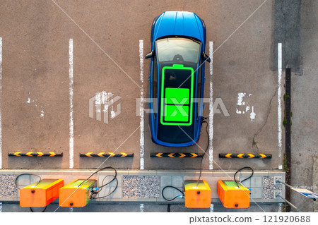 Blue electric car with power charging indicator on roof receives electricity at parking lot. Equipment available for drivers to receive electricity Blue electric car with power charging indicator on roof receives electricity at parking lot. Equipment available for drivers to receive electricity 121920688