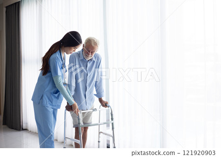 female doctor helping active senior man to walk with walker at home female doctor helping active senior man to walk with walker at home 121920903