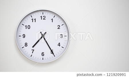 Minimalist White Clock with Silver Frame Striking 19.25/07.25 on White Background. Perfect for Time Management and Corporate Campaigns Minimalist White Clock with Silver Frame Striking 19.25/07.25 on White Background. Perfect for Time Management and Corporate Campaigns 121920991