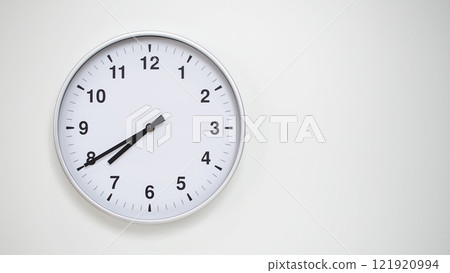Minimalist White Clock with Silver Frame Striking 19.40/07.40 on White Background. Perfect for Time Management and Corporate Campaigns 121920994