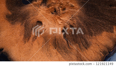 Lava ink. Paint bloom. Orange copper metal dust fluid spread in black enamel liquid sparkling surface. Round blotch spill abstract art background. 121921149