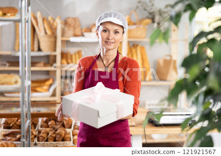 Female baker or confectioner with gift box of cake in bakery Female baker or confectioner with gift box of cake in bakery 121921567