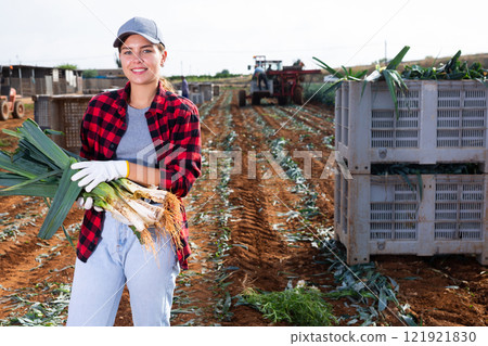 Portrait of positive girl farmer with crate of fresh leek 121921830