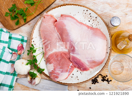 Tender raw pork steaks with garlic and herbs on plate 121921890