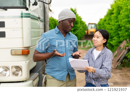 Two farm workers discussing papers standing near car Two farm workers discussing papers standing near car 121921937