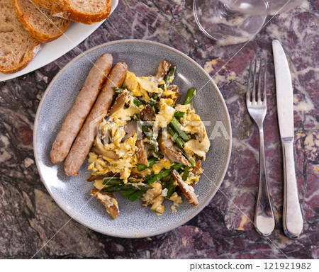 Scrambled eggs with wild mushrooms and champignons with sausages 121921982