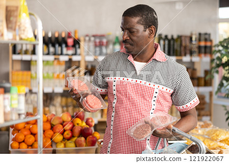 Adult man choosing hamburger in grocery store Adult man choosing hamburger in grocery store 121922067